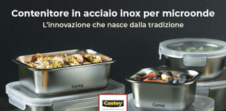 Contenitori in acciaio inox Castey con coperchi trasparenti ermetici, impilati e riempiti di insalata e frutta, su sfondo scuro con logo Trabo