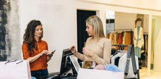 Commessa e cliente in negozio di abbigliamento durante il pagamento alla cassa, rappresentazione della gestione degli incassi nel punto vendita
