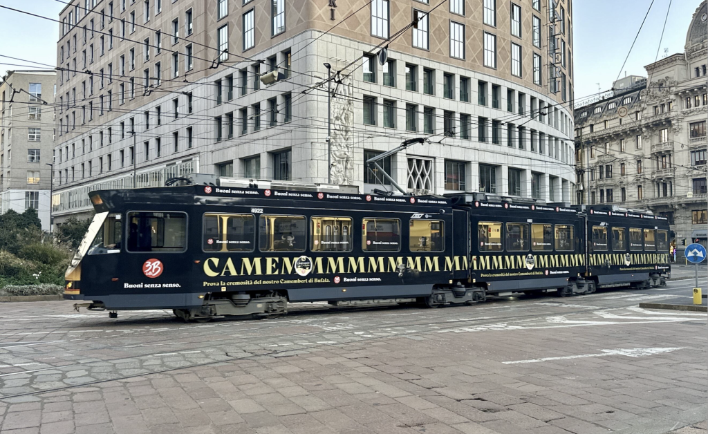 Alt Text Un tram cittadino decorato con la pubblicità del Camembert di Bufala 3B Latte per la campagna "Buoni senza senso".