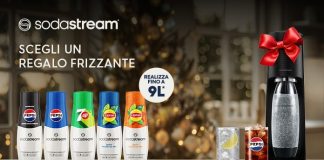 Gasatore Sodastream con fiocco rosso natalizio, affiancato da concentrati gusti Pepsi, 7Up e Lipton e bicchieri di bibite frizzanti in un'ambientazione festiva.