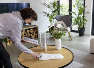 Una donna utilizza lo spolveratore Leifheit Superduster su un tavolo in legno per una pulizia casa sostenibile e profonda senza l'uso di prodotti chimici