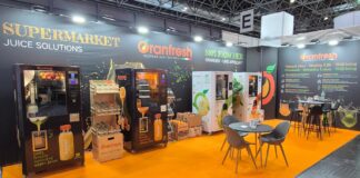 Stand fieristico di Oranfresh a Euroshop 2026 con pavimentazione arancione, macchine per spremute fresche, espositori di arance e tavoli da bar