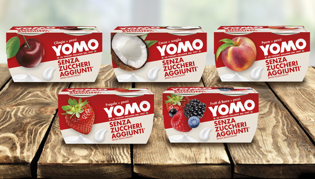 Gamma completa yogurt Yomo Senza Zuccheri Aggiunti nei gusti ciliegia, cocco, pesca, fragola e frutti di bosco su piano in legno.