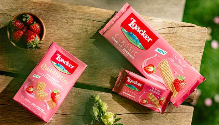 Confezioni dei nuovi wafer Loacker Strawberry (Classic e Quadratini) esposte su un tavolo di legno all'aperto con fragole fresche, novità presentata a Tuttofood 2026