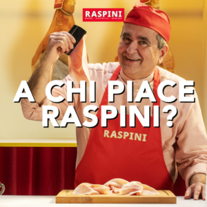 Un sorridente salumiere professionista, con grembiule rosso firmato Raspini e cappello coordinato, mostra una fetta di prosciutto cotto mentre è al bancone con i salumi sullo sfondo. In primo piano, il testo della campagna di comunicazione nazionale Raspini: "A CHI PIACE RASPINI?". Immagine che valorizza la qualità e l'artigianalità del brand in occasione di TuttoFood 2026