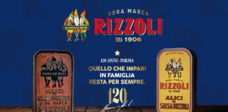Immagine celebrativa del 120° anniversario della marca Rizzoli, con il logo storico e il payoff "MANGIAR BENE". Al centro, il testo "120 ANNI - PARMA: Quello che impari in famiglia resta per sempre" e un grande numero "120" d'oro con una firma sottostante. Sotto, "5 GENERAZIONI DI ESPERIENZA ITALIANA. IL SEGRETO È RIZZOLI.". Ai lati del testo, sono presenti due lattine storiche e illustrative di Alici in Salsa Rizzoli, una più scura a sinistra e una gialla a destra, su un piano di legno con uno sfondo blu sfocato