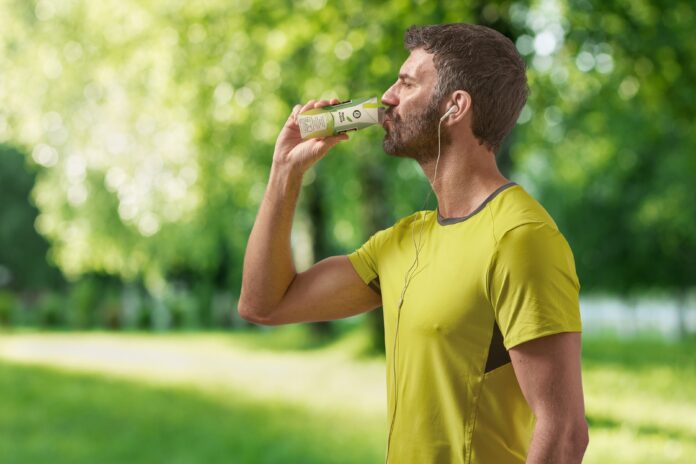 Uomo che consuma bevande funzionali in una pratica confezione Tetra Pak durante un'attività sportiva all'aperto, esempio di consumo on-the-go
