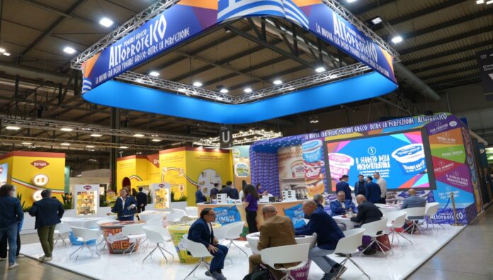 Stand espositivo Neogal a Tuttofood 2026 per il lancio del nuovo yogurt greco altoproteico con grafiche promozionali della linea e visitatori ai tavoli