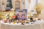 Confezione regalo e bustine assortite della linea Sir Winston Tea Bridgerton di Pompadour su un tavolo imbandito, con logo dorato Brands Award New Entry 26 in alto a destra