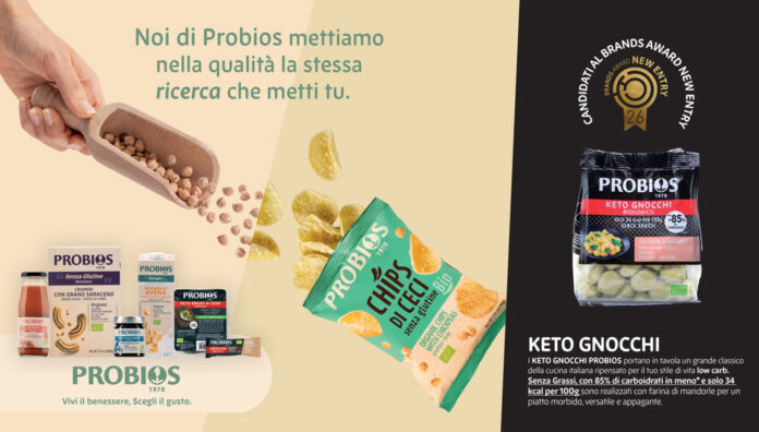 Una panoramica dei prodotti Probios esposti su uno sfondo grafico che mette in evidenza la qualità degli ingredienti biologici. A sinistra, diverse referenze tra cui pane, biscotti, succhi e una mano che versa ceci da un mestolo di legno. Al centro, una confezione di Chips di Ceci Probios aperta con chips sparse. A destra, in evidenza, la confezione di Keto Gnocchi Probios con il logo Brands Award New Entry 2026 e la descrizione dei benefici nutrizionali per uno stile di vita low carb