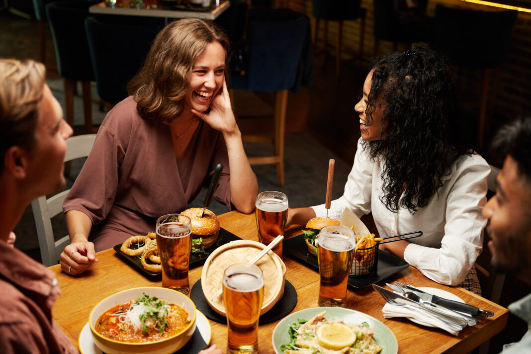 Socialità birra e cibo 2 Happy young multiracial group of friends wearing casual clothing smiling during conversation over dinner