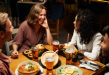 Happy young multiracial group of friends wearing casual clothing smiling during conversation over dinner