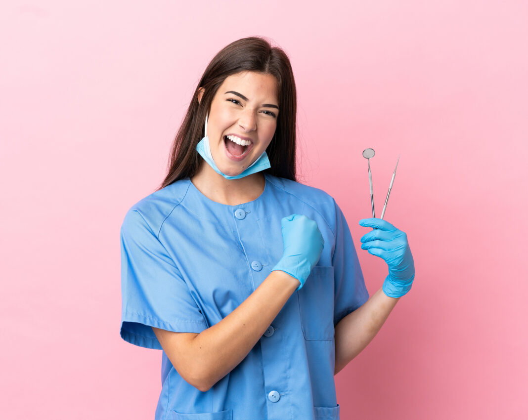Dentist,Woman,Holding,Tools,Isolated,On,Pink,Background,Celebrating,A Giovani dentisti