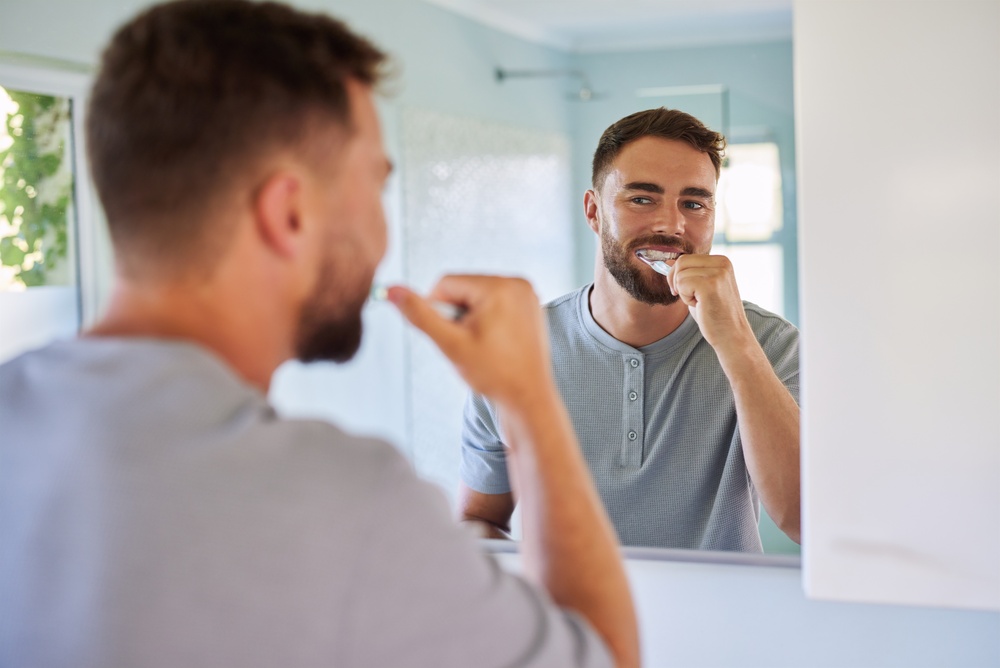 Young,Man,Brushing,Teeth,In,Bathroom,At,Home.,Reflection,Of Spazzolare i denti