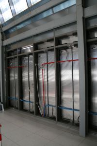 PARETI ATTIVE. Vista dall'interno dell'involucro edilizio: i pannelli di rivestimento esterno presentano sul retro moduli a serpentina derivati da componenti prodotti in serie per la costruzione di celle frigorifere, collegati mediante circuiti idronici alla pompa di calore. La regolazione del funzionamento è affidata a un building management system dotato di infrastruttura wireless.