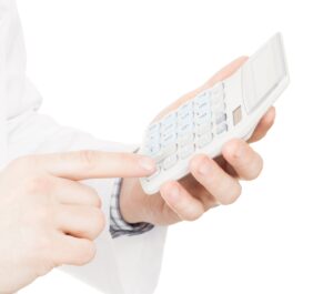 Medical doctor with a calculator in his left hand calculating costs and revenues in physician practice and hospital fees