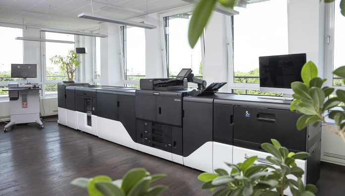 TASKalfaPro15000c_1392x792 Kyocera TASKalfa Pro 15000c installata in un reparto stampa professionale, con unità inkjet a foglio e finitura inline, in un ambiente luminoso con piante e ampie finestre