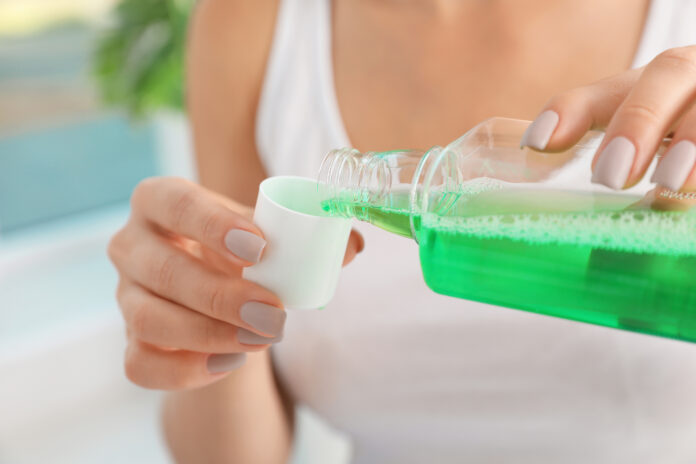 Woman pouring mouthwash from bottle into cap, closeup. Teeth car
