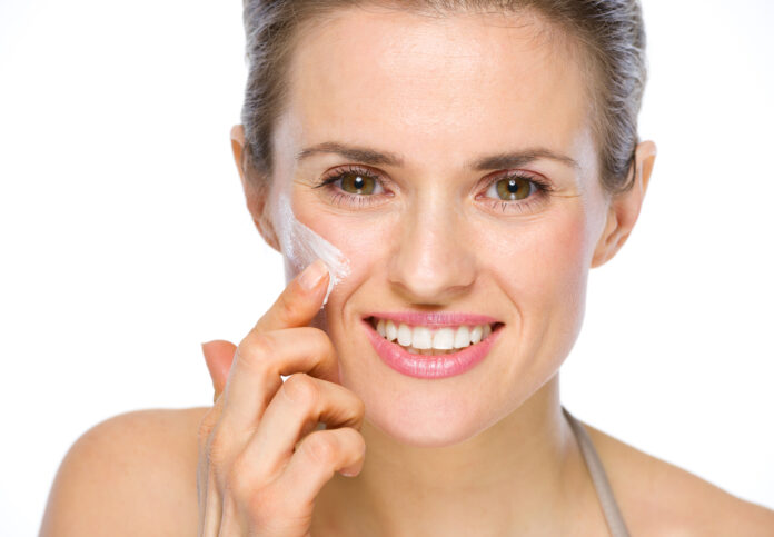 Una donna applica della crema sul viso