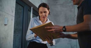 Consegna di un pacco a domicilio: una cliente firma la ricezione mentre il corriere gestisce la spedizione, esempio di delivery experience digitale migliorata con le soluzioni di messaggistica LINK Mobility.