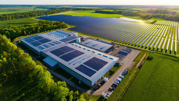 Huawei_AdobeStock_2019867229_Aerial view of a large industrial building with solar panels on its roof, next to a solar farm Huawei