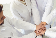 Giornata del personale sanitario: il valore del team multidisciplinare nella gestione della complessità Professionisti sanitari in camice bianco con le mani unite in segno di collaborazione