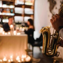 Saxophonist's hands while playing jazz. Musician hold sax at romantic date on Valentine's Day in restaurant. Man performing on saxophone at party or wedding. Jazz music concept closeup. Space for text