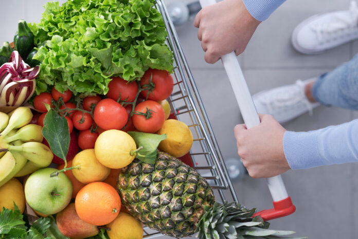 AdobeStock_492868809_carrello-ortofrutta_Woman pushing a shopping cart full of vegetables and fruits