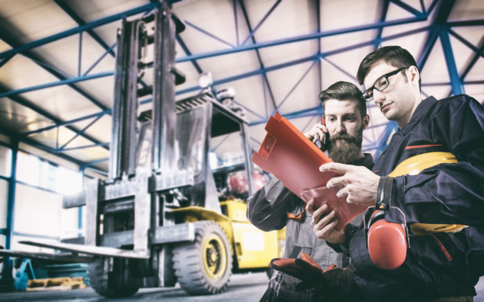 Workers in protective uniform in front of forklift