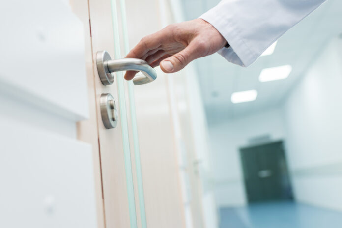 cropped view of male doctor holding door handle in hospital maniglie