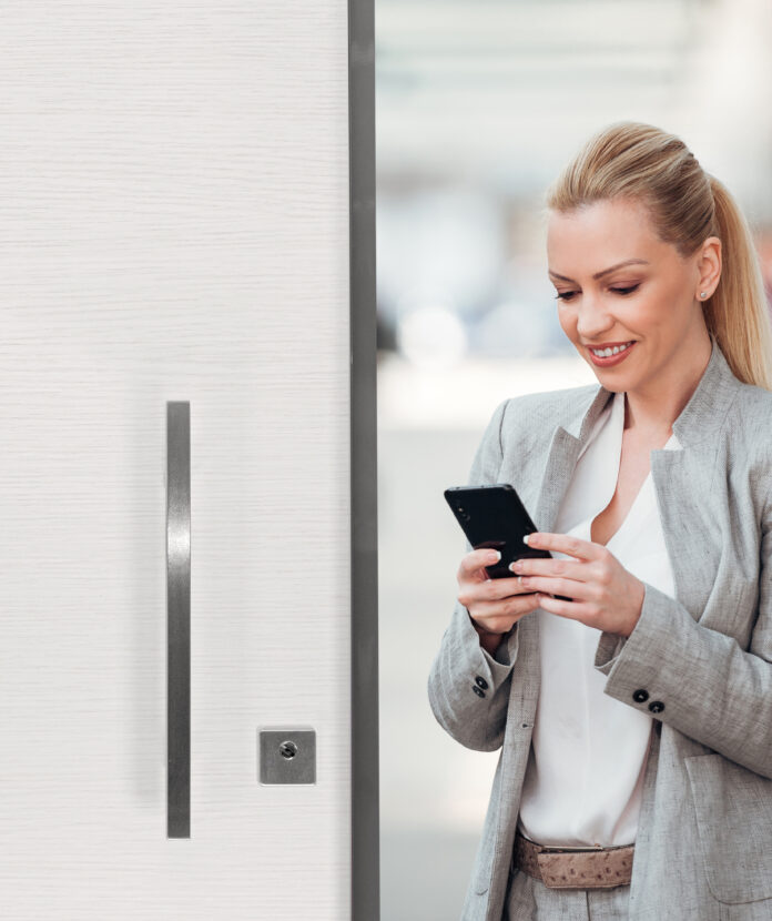 Beautiful smiling businesswoman using smartphone on the city str