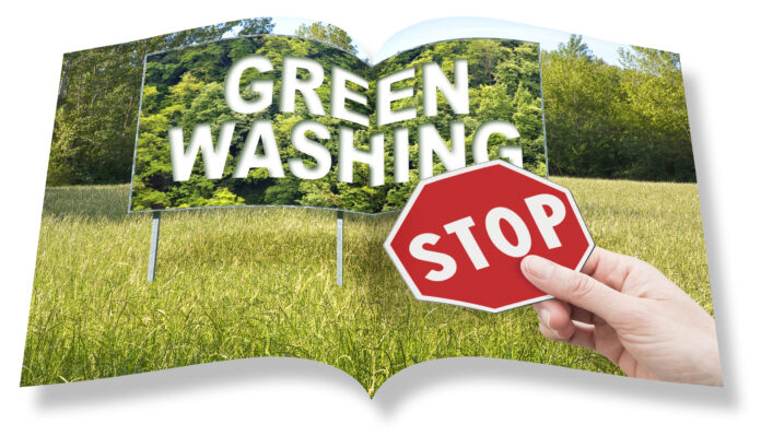 Stop Greenwashing concept with advertising signboard in a rural scene with trees on background and hand holding a stop sign greenwashing green washing