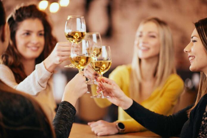 Girlfriends drinking wine and chatting while sitting in the bar.